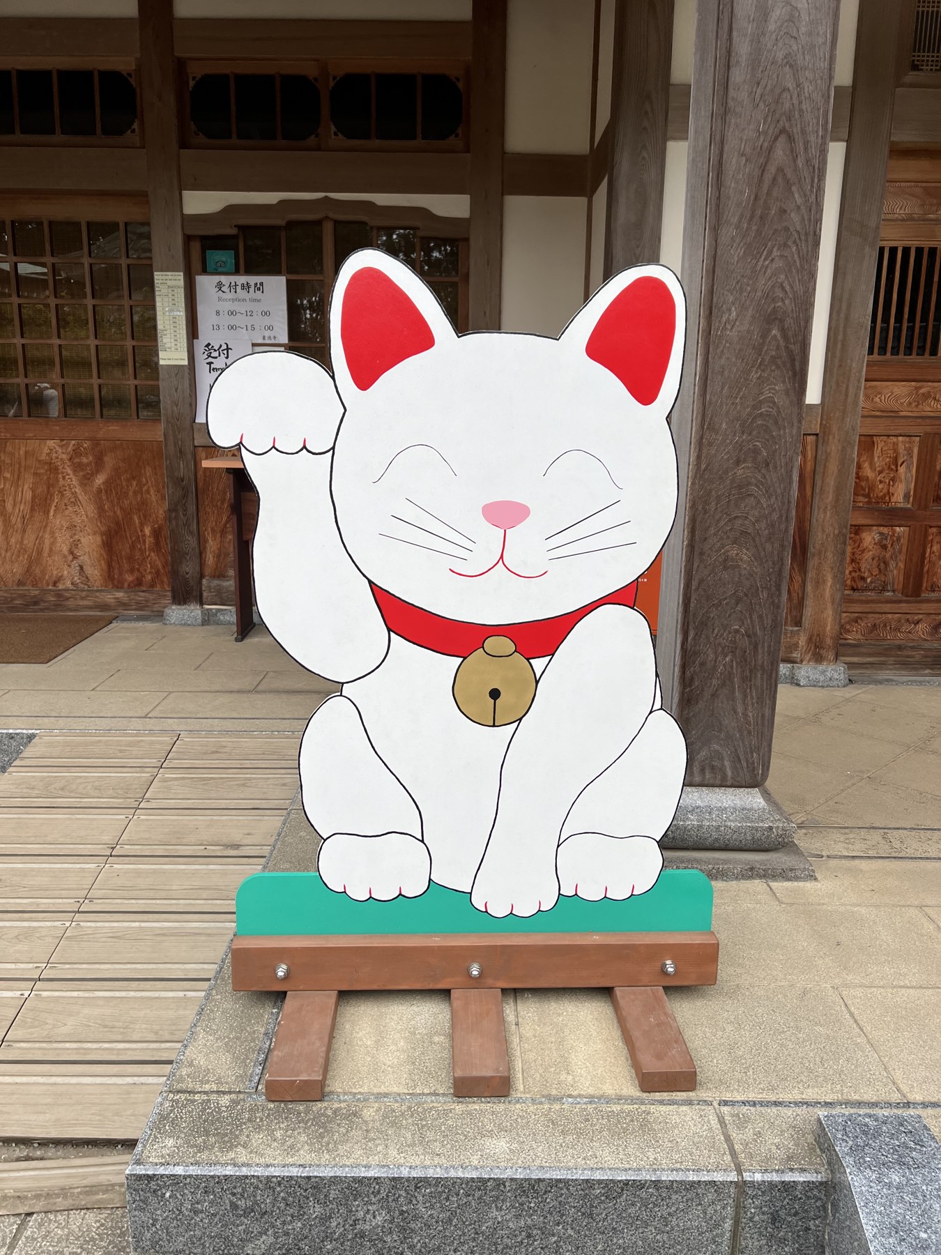 A life-size painted wooden cutout of a maneki-neko standing outside the temple office at Gotokuji