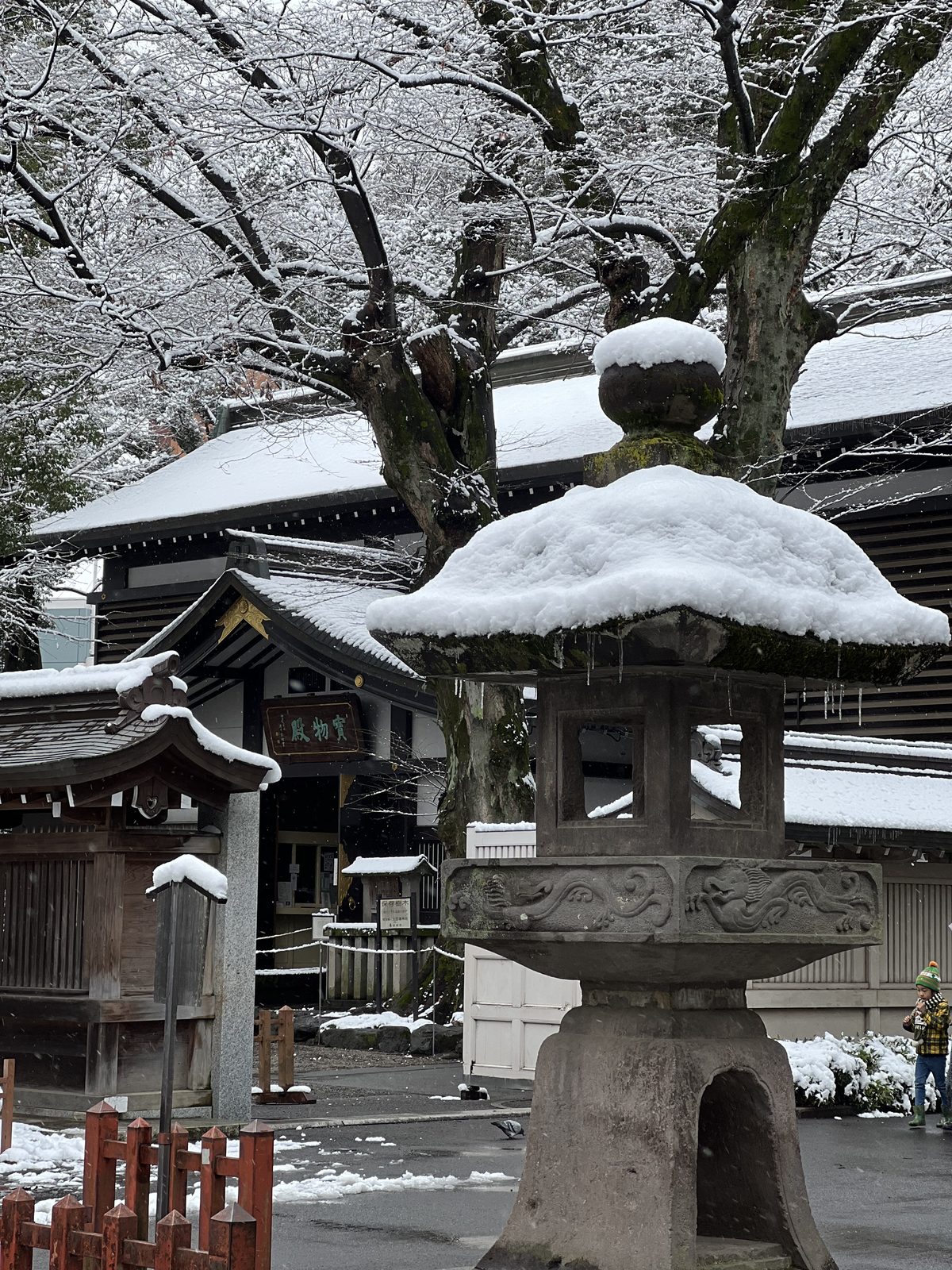 A stone lantern with snow on its roof at a shrine